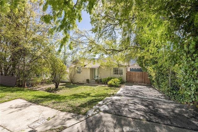 view of front of home featuring a front yard, fence, and stucco siding