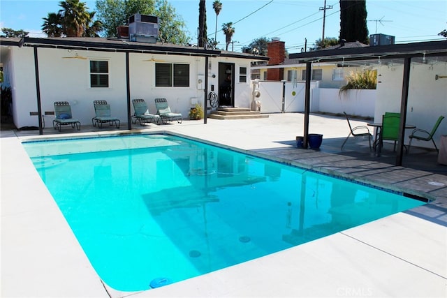 rear view of house with fence, a fenced in pool, central AC unit, ceiling fan, and a patio area