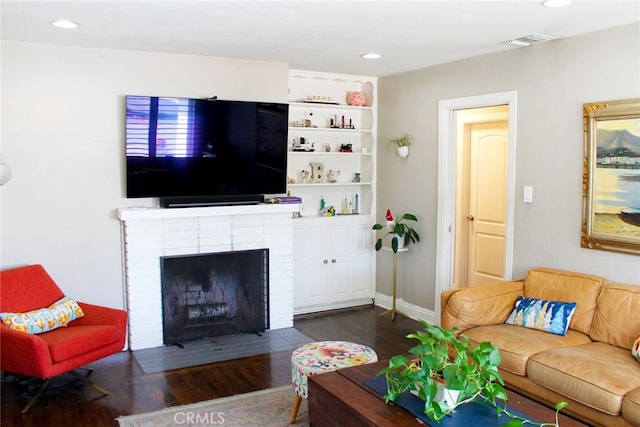 living room with visible vents, baseboards, recessed lighting, a fireplace, and wood finished floors