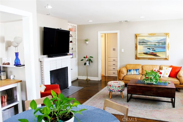 living area with visible vents, a brick fireplace, baseboards, recessed lighting, and wood finished floors