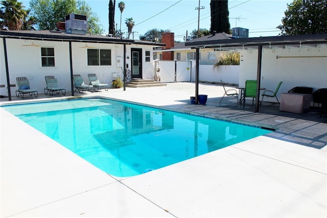 view of pool with a gate, fence, cooling unit, a fenced in pool, and a patio area