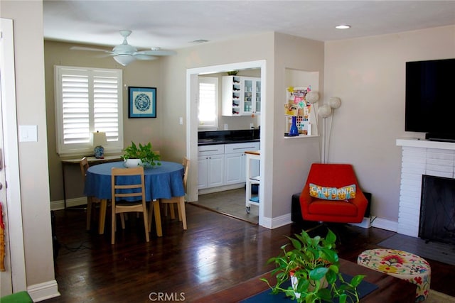 living room with visible vents, ceiling fan, baseboards, a fireplace, and dark wood-style flooring