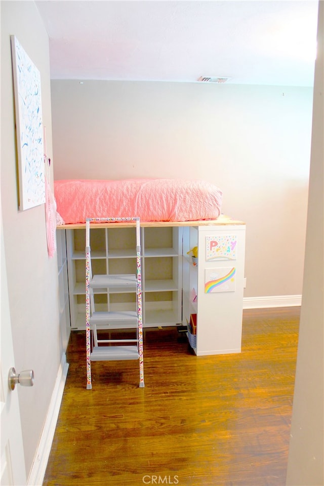 unfurnished bedroom featuring visible vents, wood finished floors, and baseboards