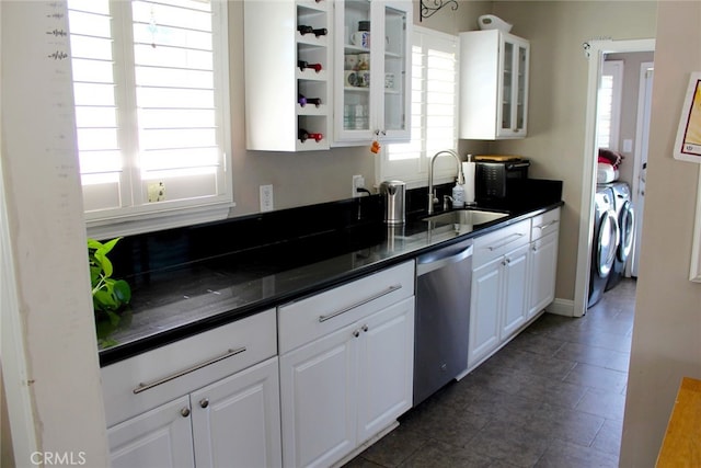 kitchen featuring a sink, washer and dryer, dark countertops, white cabinets, and dishwasher