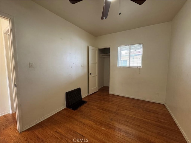 unfurnished bedroom featuring a ceiling fan, wood finished floors, a closet, and baseboards