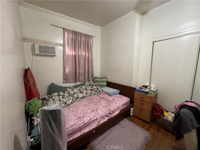 bedroom featuring a wall unit AC and wood finished floors