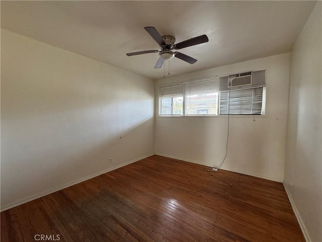 empty room with a wall unit AC, wood finished floors, baseboards, and ceiling fan