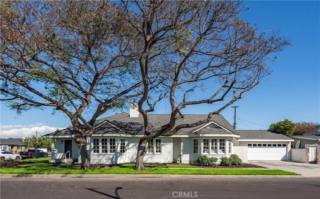 ranch-style home with a garage, concrete driveway, a chimney, and a front yard