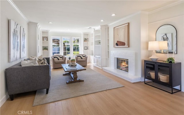 living area with recessed lighting, ornamental molding, a brick fireplace, wood finished floors, and baseboards