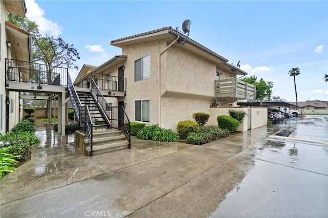 view of side of property featuring stairway and stucco siding