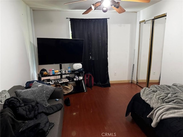 bedroom featuring baseboards, wood finished floors, and a ceiling fan