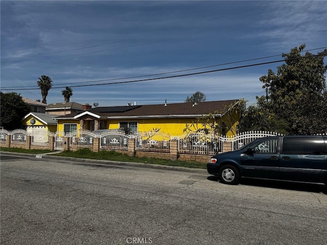 view of front of house featuring a fenced front yard, roof mounted solar panels, and a gate