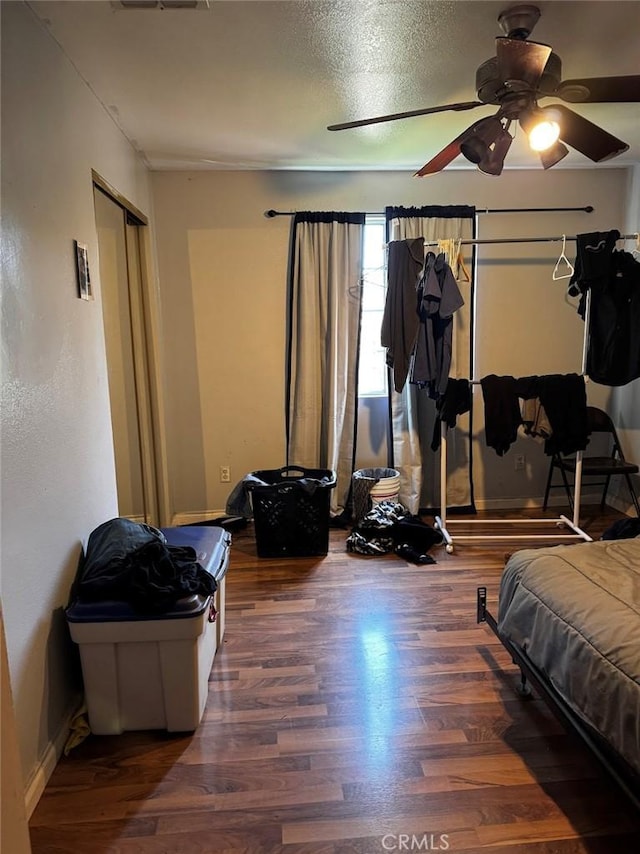 bedroom with visible vents, a ceiling fan, wood finished floors, a closet, and baseboards