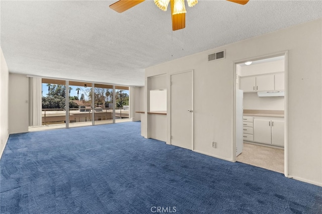 unfurnished living room with visible vents, a textured ceiling, carpet, baseboards, and ceiling fan