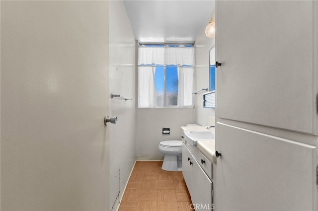 bathroom with vanity, toilet, and baseboards