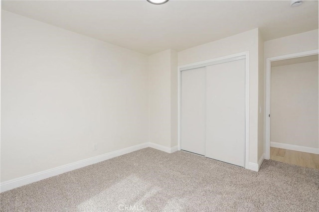 unfurnished bedroom with carpet floors, baseboards, and a closet