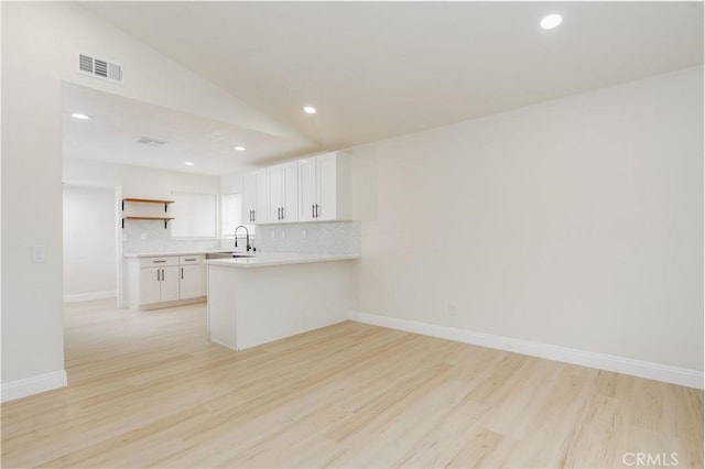 kitchen featuring light countertops, visible vents, light wood-style flooring, backsplash, and white cabinetry