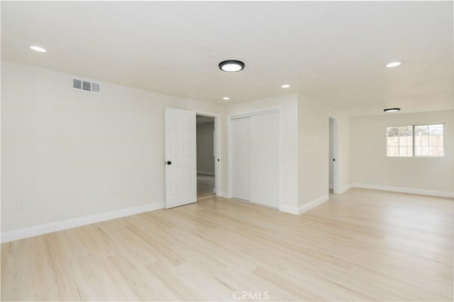 empty room with light wood-type flooring, baseboards, visible vents, and recessed lighting