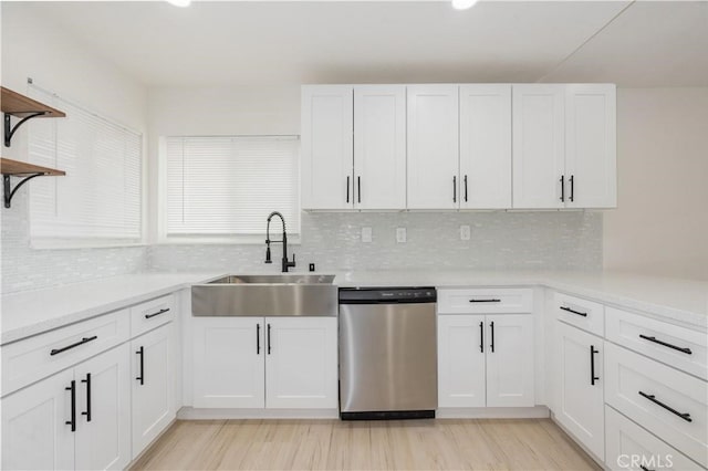 kitchen featuring open shelves, light countertops, white cabinetry, a sink, and dishwasher