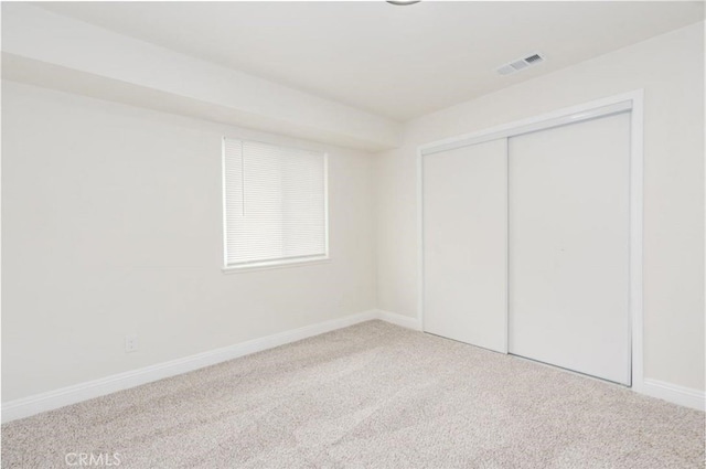 unfurnished bedroom with carpet floors, a closet, visible vents, and baseboards