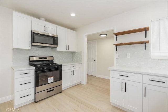 kitchen with baseboards, white cabinets, stainless steel appliances, light wood-style floors, and open shelves