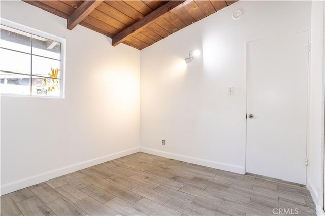 empty room with wooden ceiling, baseboards, light wood finished floors, and beam ceiling