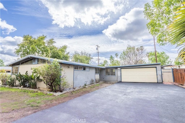 view of front of home featuring a garage, fence, and aphalt driveway