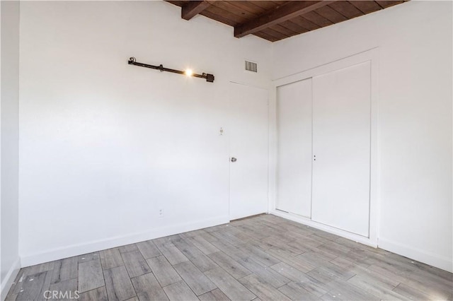 spare room featuring wooden ceiling, baseboards, light wood-style floors, and beam ceiling