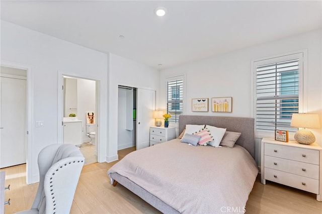 bedroom featuring recessed lighting, light wood-type flooring, and ensuite bath