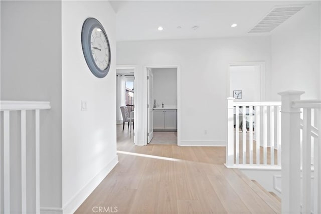 hallway featuring recessed lighting, baseboards, and light wood finished floors