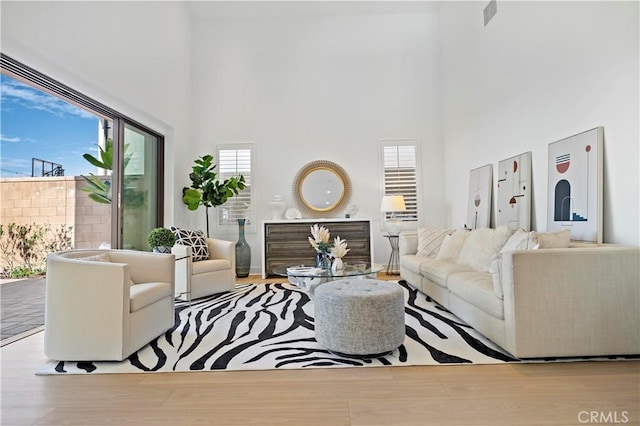 living room with wood finished floors, visible vents, and a towering ceiling