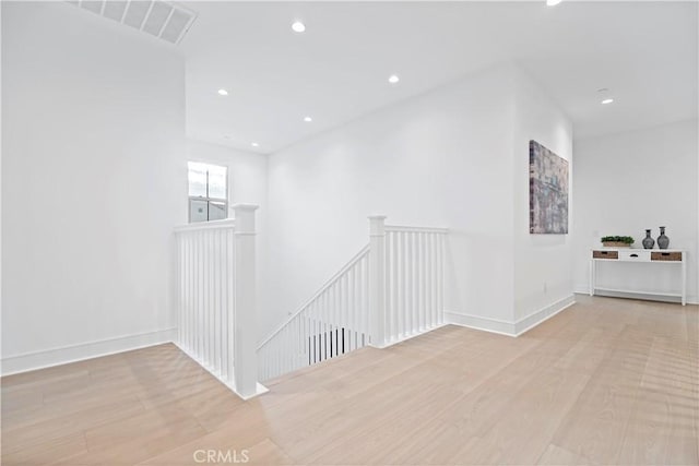 hall featuring an upstairs landing, visible vents, recessed lighting, and wood finished floors