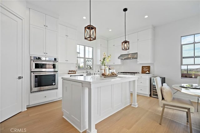 kitchen with under cabinet range hood, white cabinetry, appliances with stainless steel finishes, and light countertops