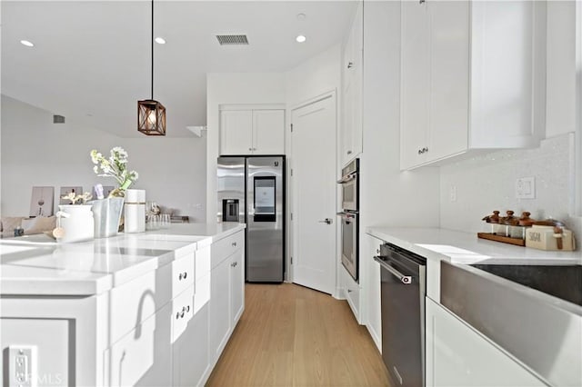 kitchen featuring white cabinets, light wood finished floors, visible vents, and appliances with stainless steel finishes