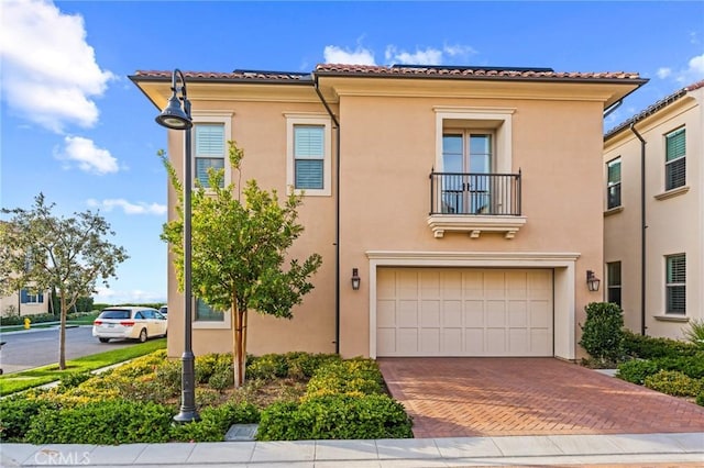 view of front of house with stucco siding, decorative driveway, a garage, and a tiled roof