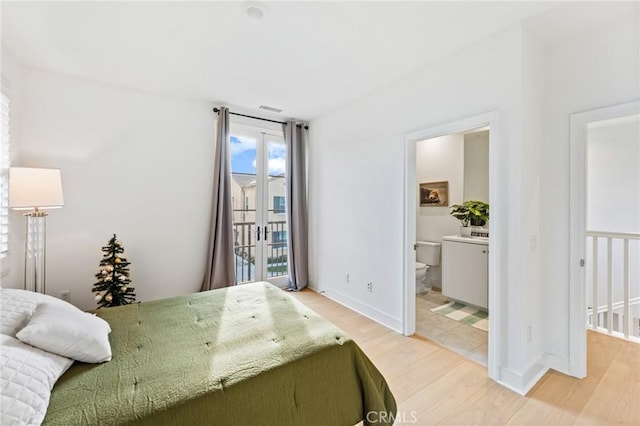 bedroom featuring light wood-style flooring, baseboards, connected bathroom, and access to outside