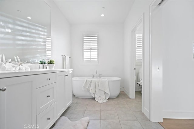 bathroom with tile patterned floors, a soaking tub, recessed lighting, and vanity