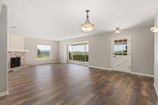 unfurnished living room with visible vents, a fireplace, baseboards, and dark wood finished floors