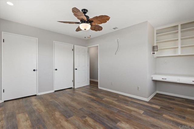 unfurnished bedroom with baseboards, visible vents, built in desk, and wood finished floors