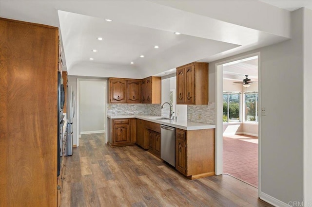 kitchen featuring tasteful backsplash, brown cabinetry, dark wood-style floors, stainless steel appliances, and light countertops