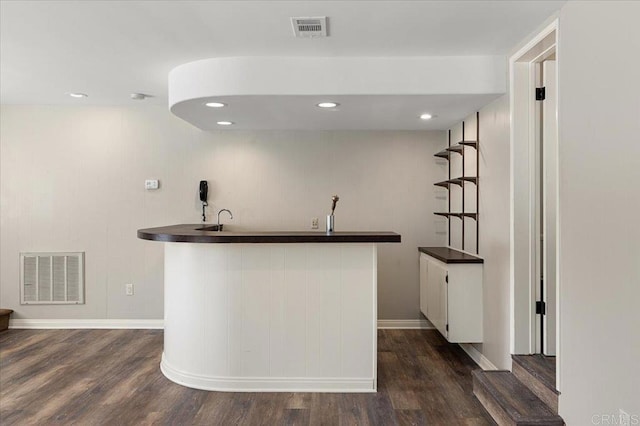 bar featuring dark wood finished floors, visible vents, and wet bar