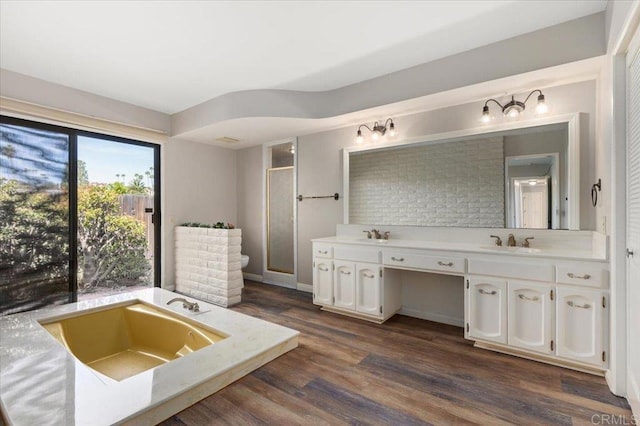 bathroom with double vanity, a stall shower, wood finished floors, a sink, and a bath