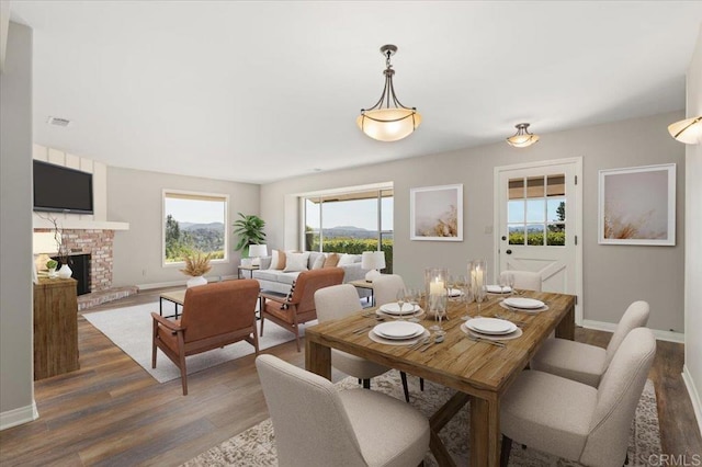 dining area with a fireplace, baseboards, and wood finished floors