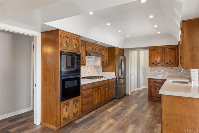 kitchen featuring dark wood finished floors, under cabinet range hood, light countertops, black appliances, and a sink