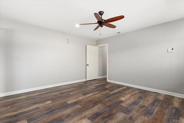 empty room featuring dark wood-style floors, a ceiling fan, visible vents, and baseboards