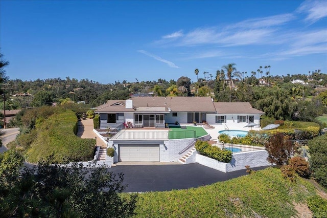 ranch-style house with an outdoor pool, a sunroom, stairs, fence, and a patio area