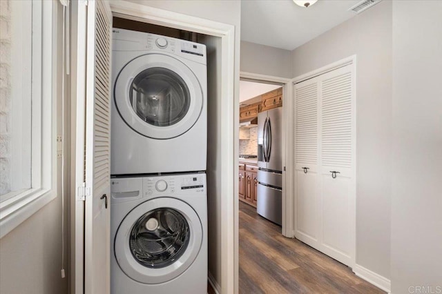 washroom featuring laundry area, baseboards, visible vents, dark wood-style floors, and stacked washing maching and dryer