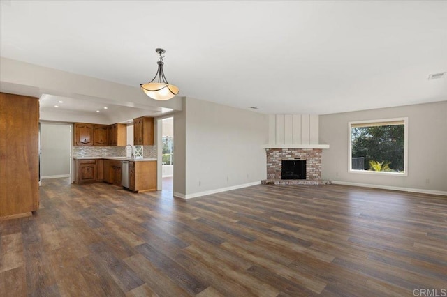 unfurnished living room featuring dark wood-style flooring, a fireplace, and baseboards