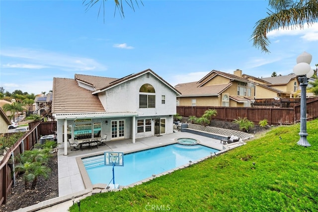 rear view of property with a fenced backyard, a tiled roof, a lawn, stucco siding, and a patio area