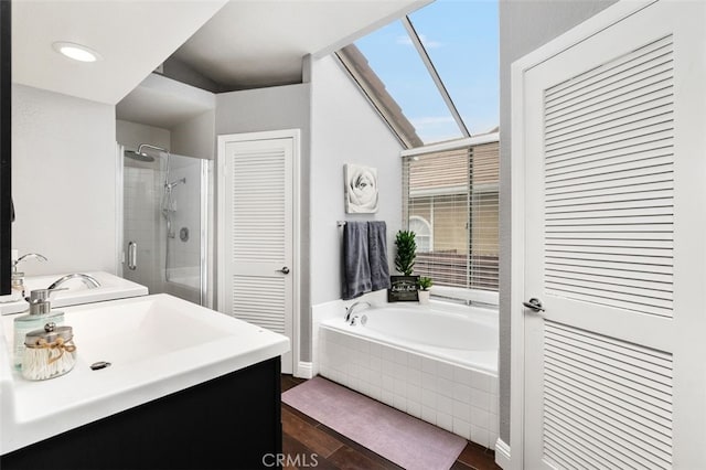 bathroom featuring a stall shower, a skylight, wood finished floors, vanity, and a bath